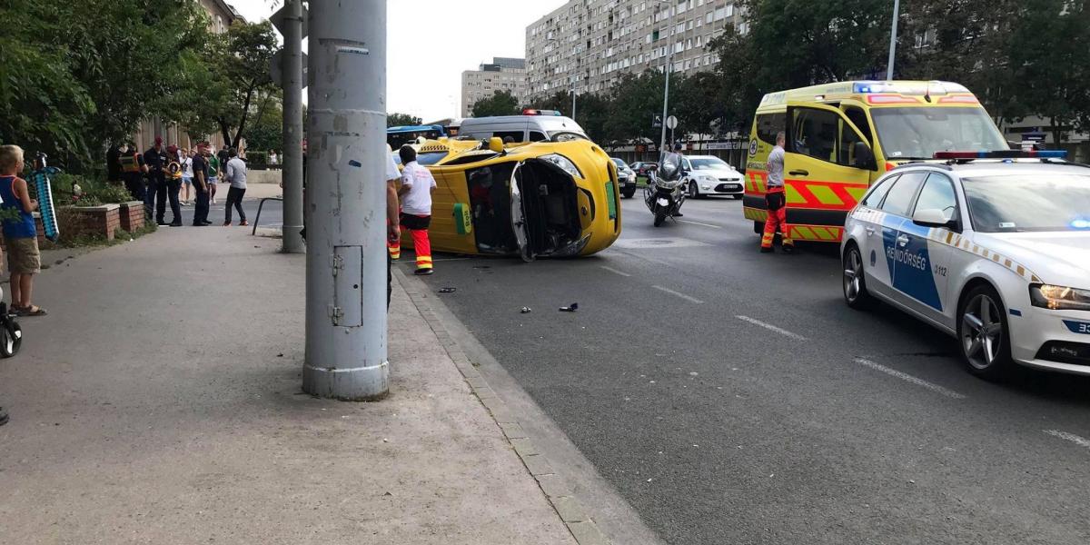 Mentősök, rendőrök a Szentendrei úton felborult taxi körül