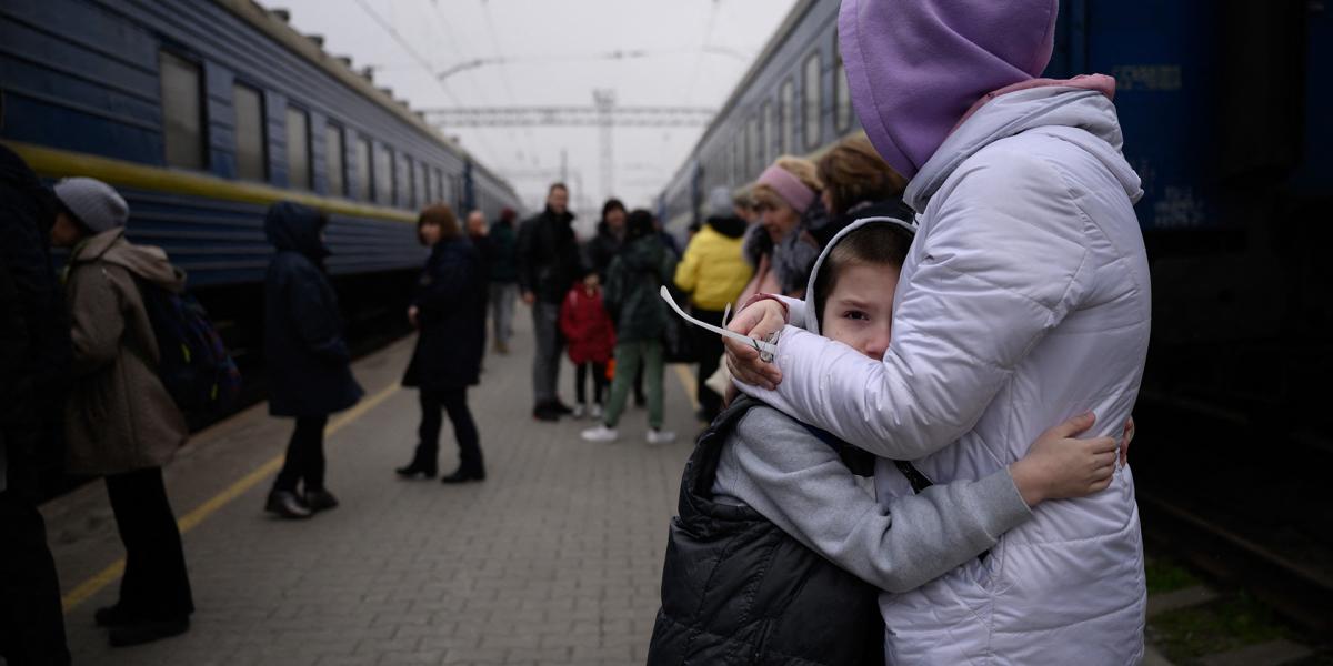 Egy nő megölel egy gyermeket, miközben egy vonat indulni készül a dél-ukrajnai Zaporijia főpályaudvaráról 2022. április 17-én.