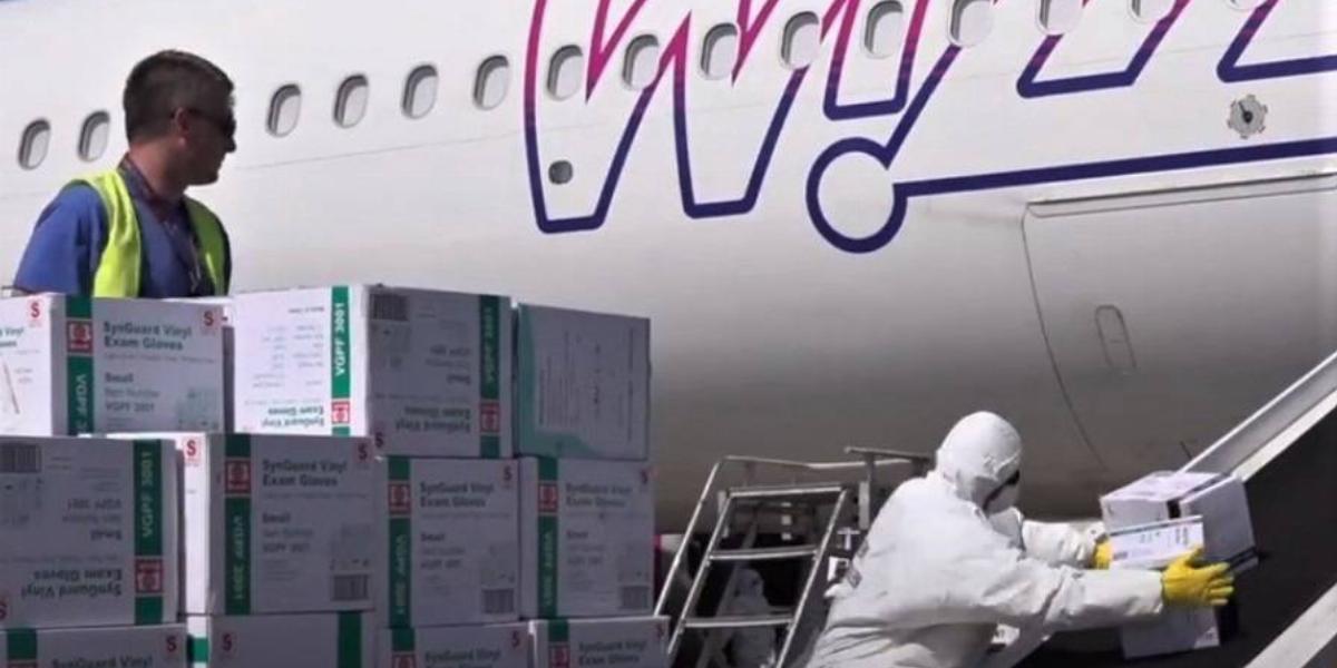 Védőruhás munkás pakolka le egy Wizz Air-gép fedélzetén hozott felszereléseket, 2020. április 18-án a ferihegyi reptéren