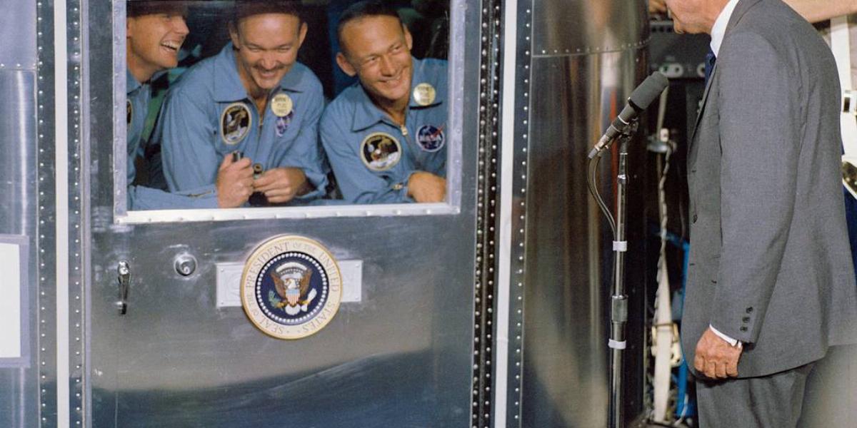 A mobil karanténban fogadják az Apollo–11 űrhajósai Richard M. Nixon elnök üdvözletét a USS Hornet fedélzetén. Balról Neil Armstrong, Michael Collins és Edwin Aldrin