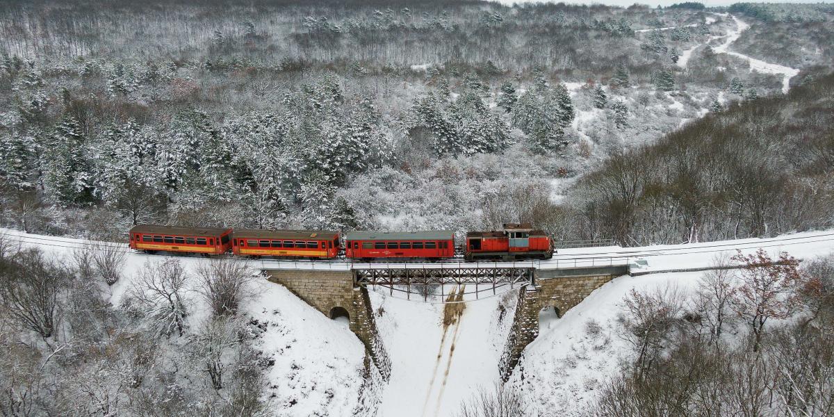 Személyvonat közlekedik a behavazott Bakonyban, Eplény és Veszprém között, az eplényi viaduktoknál  2023. január 22-én.