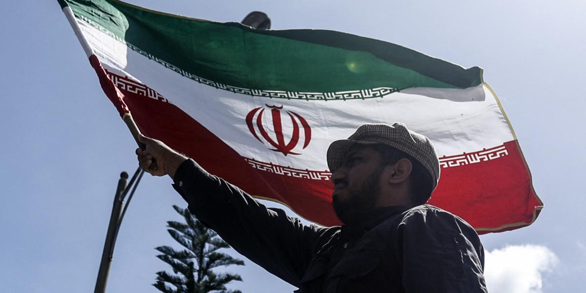 Egy férfi iráni zászlót lenget az iráni caracasi nagykövetségnél 2025. június 17-én