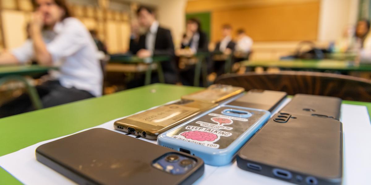 Az előtérben a telefonok, a háttérben a diákok