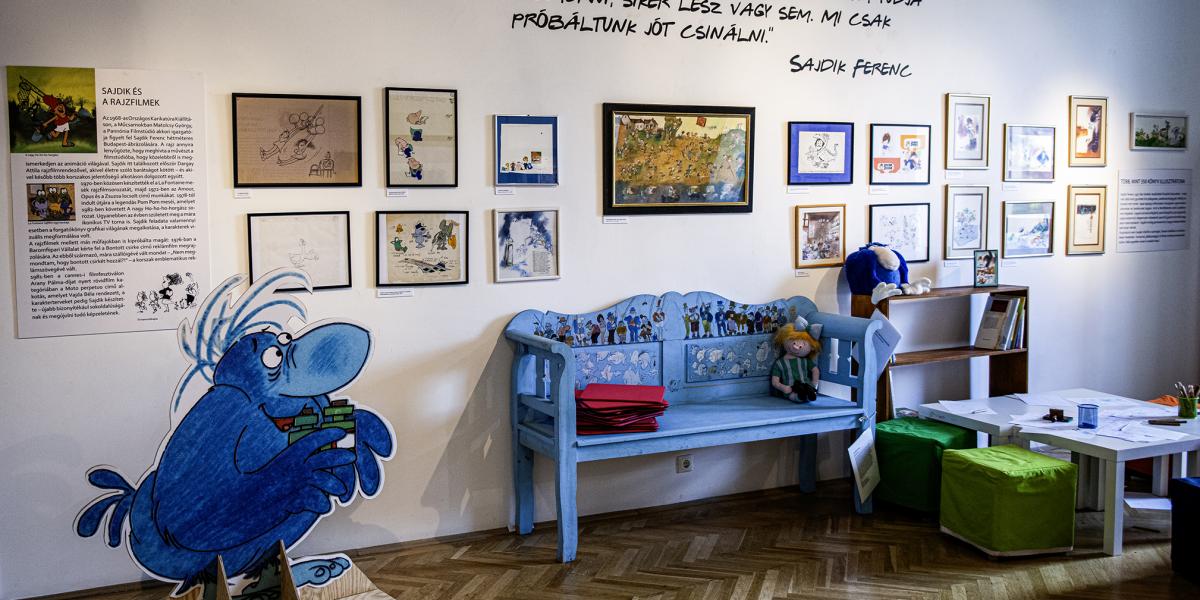 A tárlaton Sajdik Ferenc számos mesefigurája feltűnik, mint például a csokoládéért rajongó Gombóc Artúr