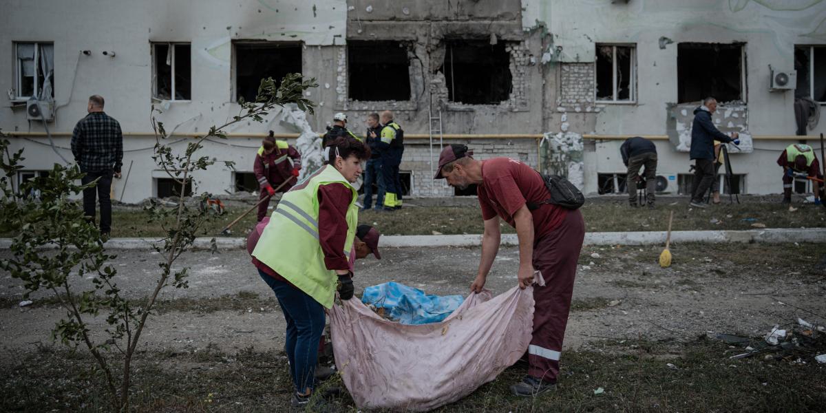 Városi dolgozók takarítják el a törmeléket egy lerombolt lakóépület elől, miután Harkivban légitámadást hajtottak végre 2025. augusztus 18-án
