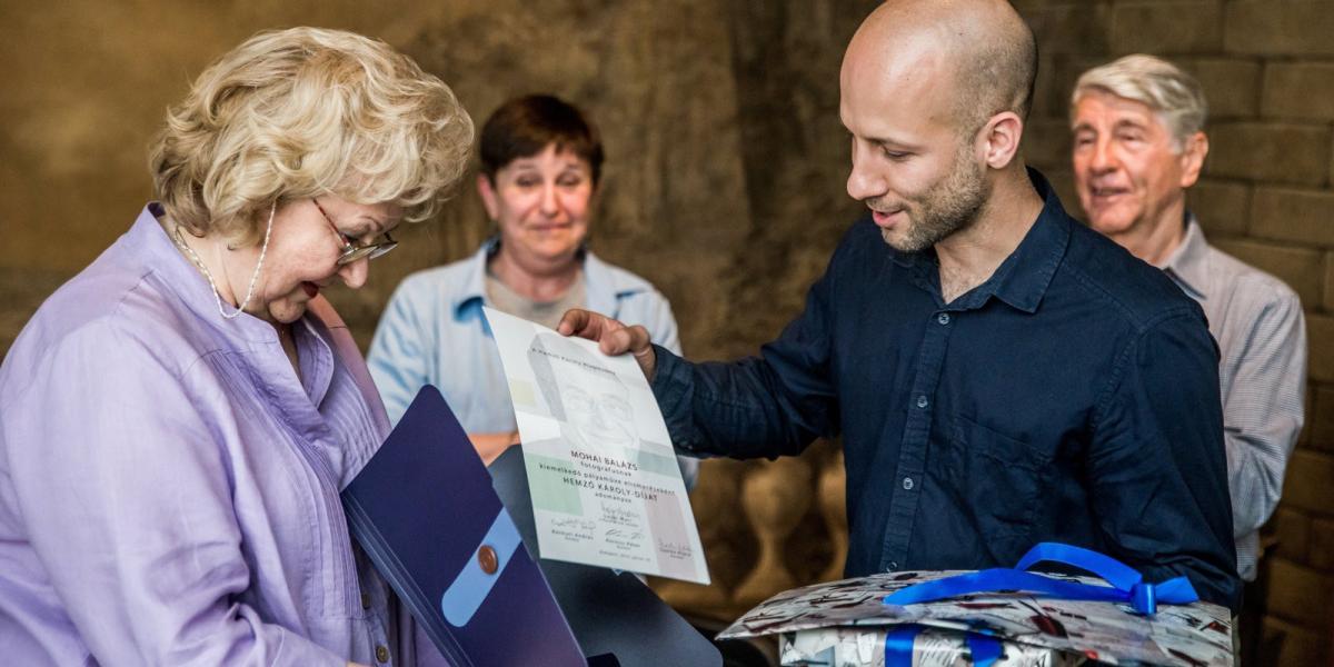 Mohai Balázs, az MTI/MTVA fotóriportere átveszi a Hemző Károly-díjat Lajos Maritól, Hemző Károly fotográfus özvegyétől a díjátad