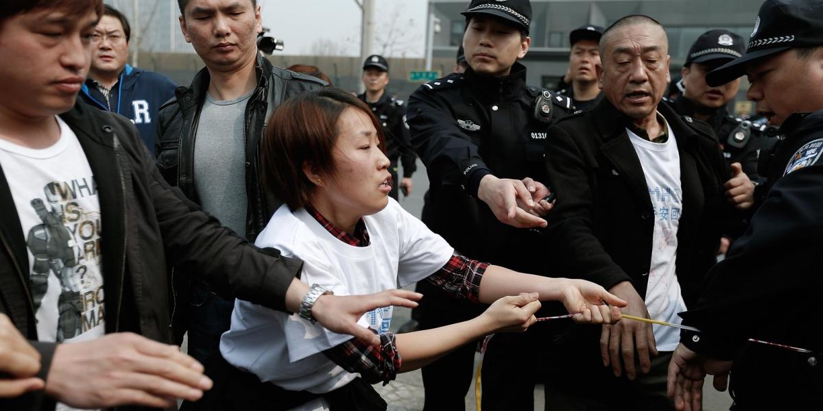 Dühös hozzátartozók mennek neki a rendőröknek a pekingi maláj nagykövetség épülete előtt. Fotó: Lintao Zhang/Getty Images