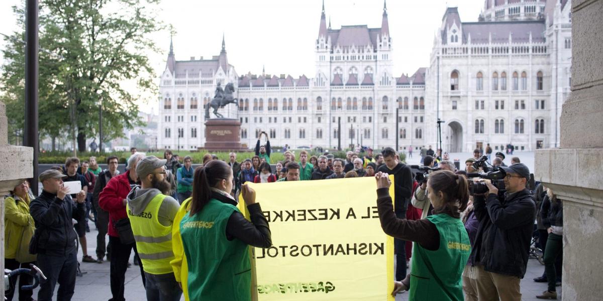 Greenpeace-aktivisták transzparenst tartanak a Vidékfejlesztési Minisztérium előtt a Kettős Mérce blog demonstrációján 2014. ápr