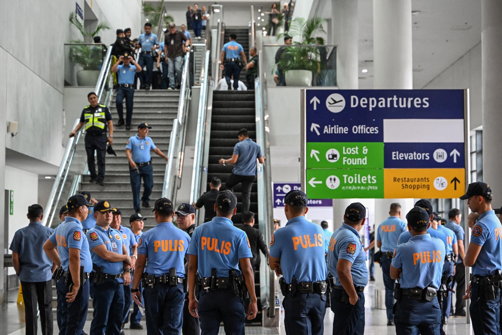 Rendőrök várnak Rodrigo Duterte volt Fülöp-szigeteki elnökre a manilai repülőtéren 2025. március 10-én