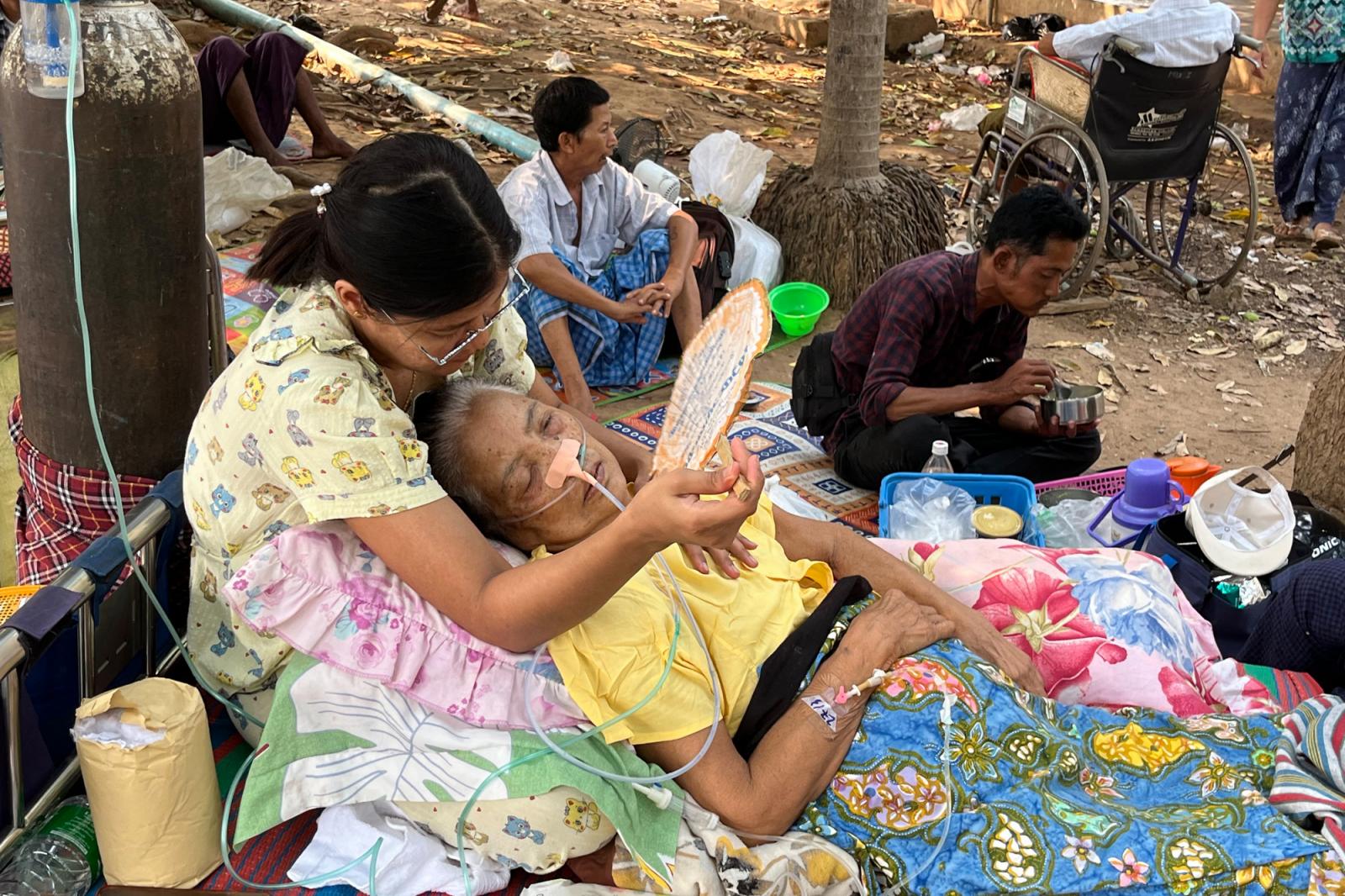 Mentőegységek emelnek ki egy férfit egy összeomlott épület törmelékei közül Bangkokban