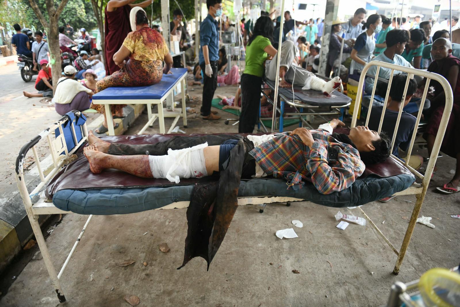 Mentőegységek emelnek ki egy férfit egy összeomlott épület törmelékei közül Bangkokban