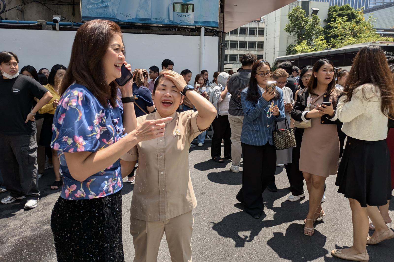 Mentőegységek emelnek ki egy férfit egy összeomlott épület törmelékei közül Bangkokban