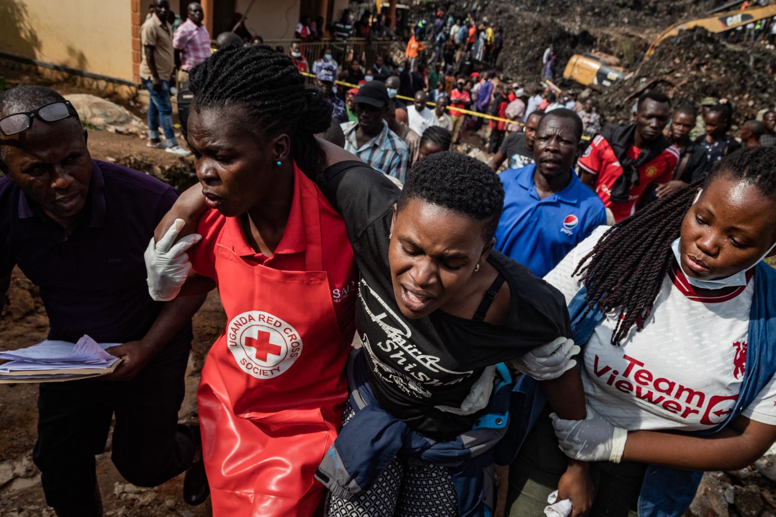 A Vöröskereszt munkatársai támogatnak egy gyászolót, aki elvesztette lányát és testvérét egy szemétlerakó-omlásban, Kampalában 2024. augusztus 10-én. Nyolcan vesztették életüket, köztük két gyermek