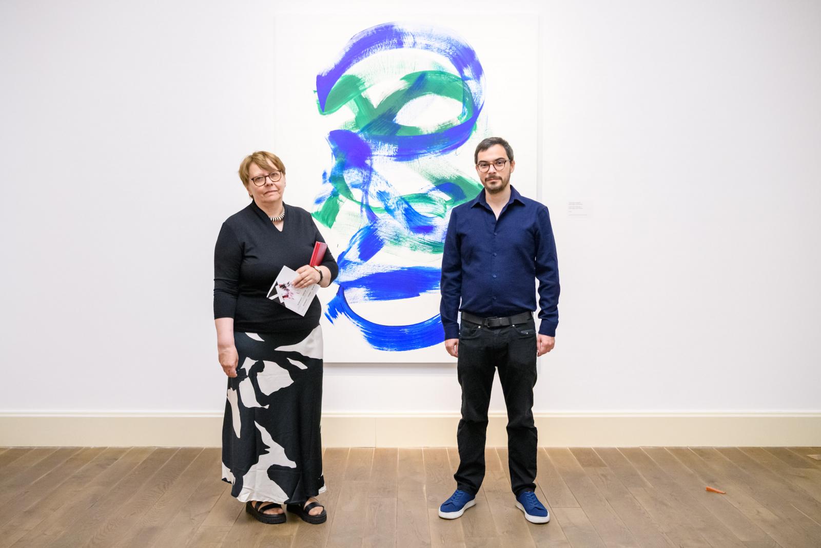 A tárlat kurátorai, Geskó Judit és Fehér Dávid a „Csak egyre kékebb” Hommage à Tolnai Ottó című festmény előtt (2025)