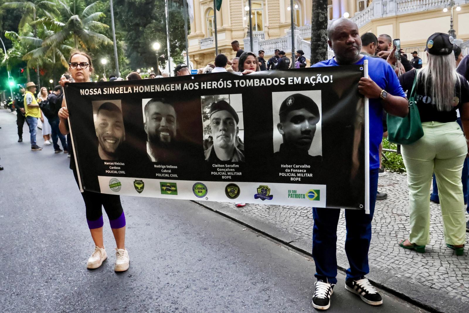 Rióban tüntettek a razzia ellen és mellett is. Itt egy transzparens a négy áldozatul esett rendőr arcképével