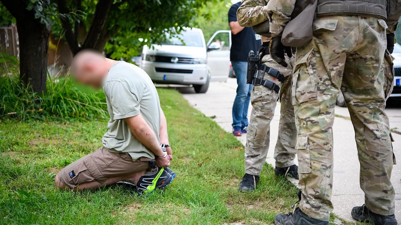 Elfogott gödöllői gyanúsított térdel,mellette TEK-kommandósok állnak