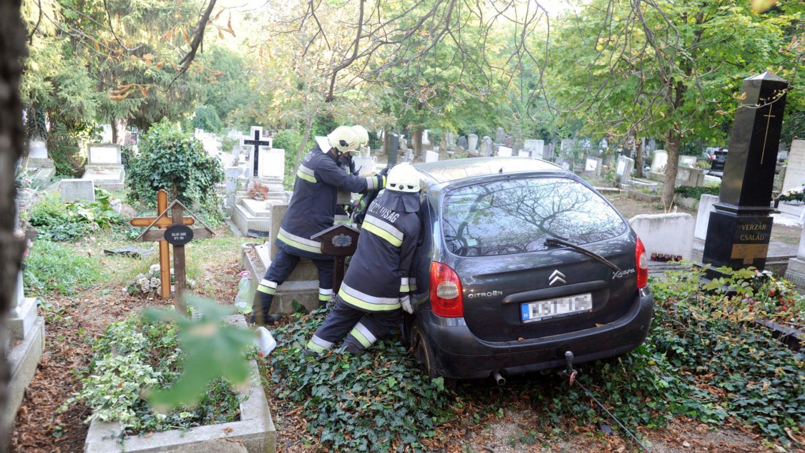 Tűzoltók dolgoznak az autó műszaki mentésén a Farkasréti temetőben