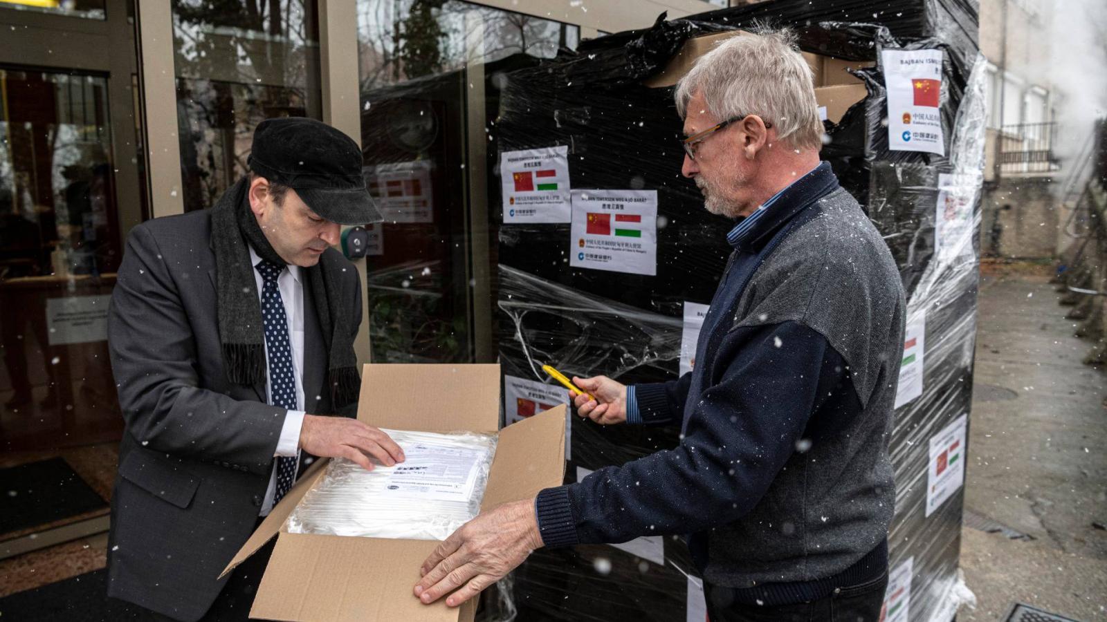 Horpácsy Balázs, az Állami Egészségügyi Ellátó Központ (ÁEEK) főigazgató-helyettese (b) és munkatársa kinyit egy dobozt a China Construction Bank (Europe) adományából, amely Párizsból érkezett a központba 2020. március 23-án