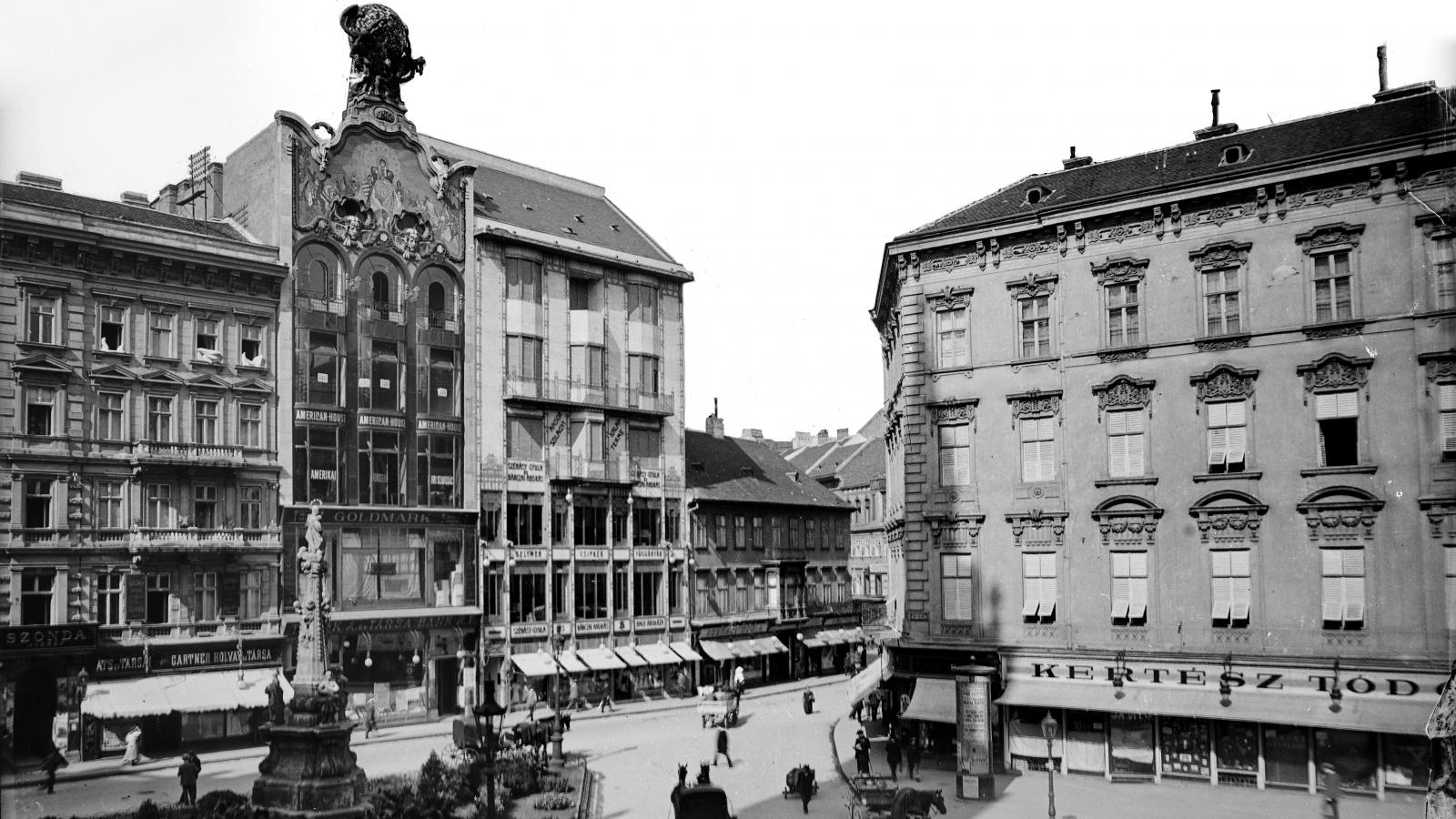 A tetődíszes háztól jobbra a Szervita tér 2., mellette pedig a Kristóf tér 4. Mindkét épületben Szénásy-üzlet működött