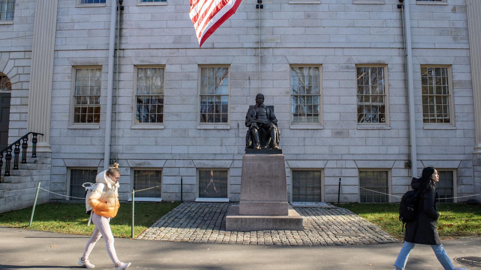 John Harvard puritán lelkipásztor szobra a világhírű egyetem campusán. Nehéz csatának néz elébe