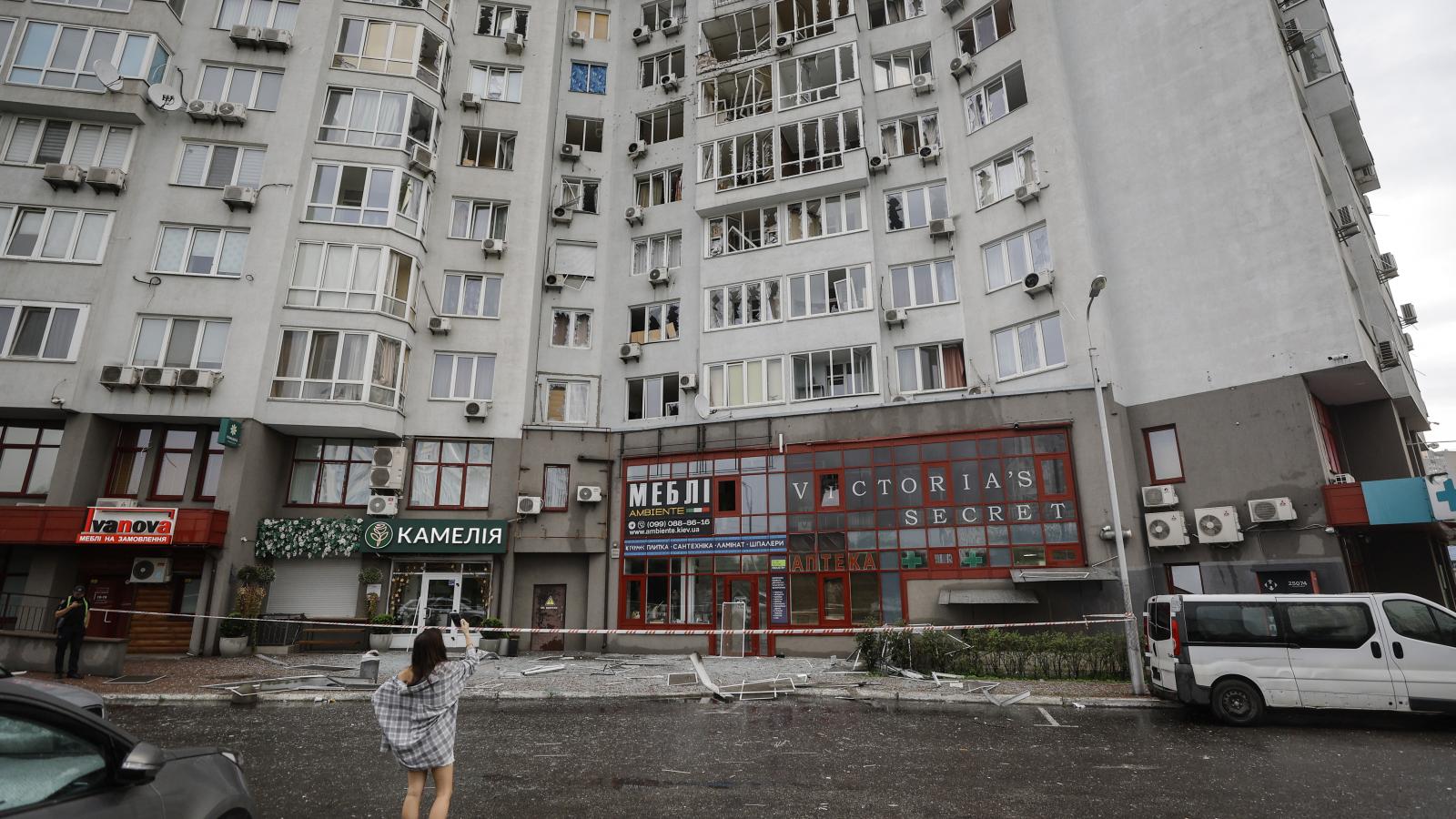 A rongálás nyomait fotózza egy nő egy kijevi lakótömbnél, amelyet orosz légicsapás ért 2025. július 28-ra virradóan