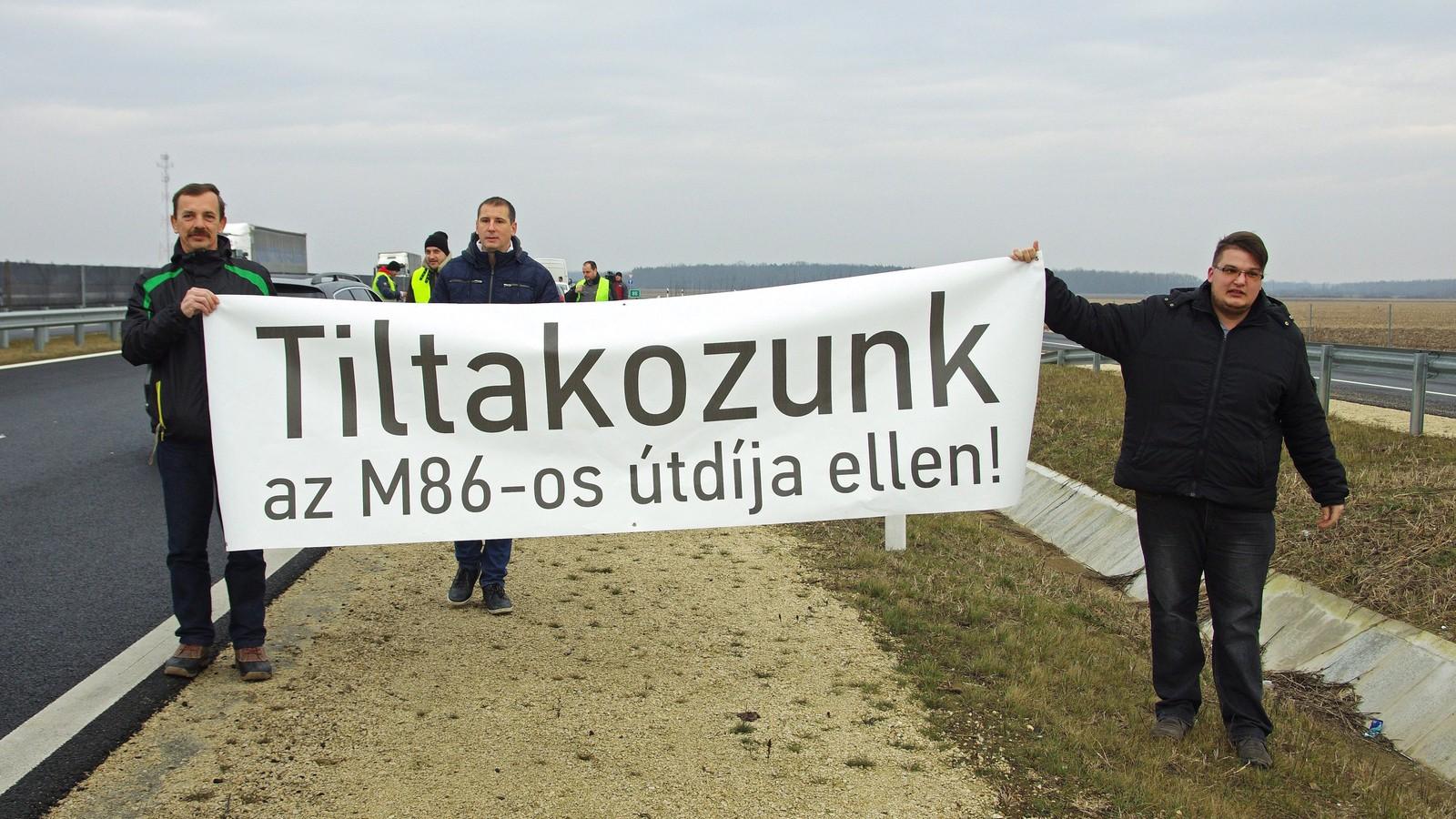 Résztvevők Tiltakozunk az M86-os útdíja ellen! feliratú transzparenst tartanak a kezükben Szombathely határában. MTI Fotó: Büki 