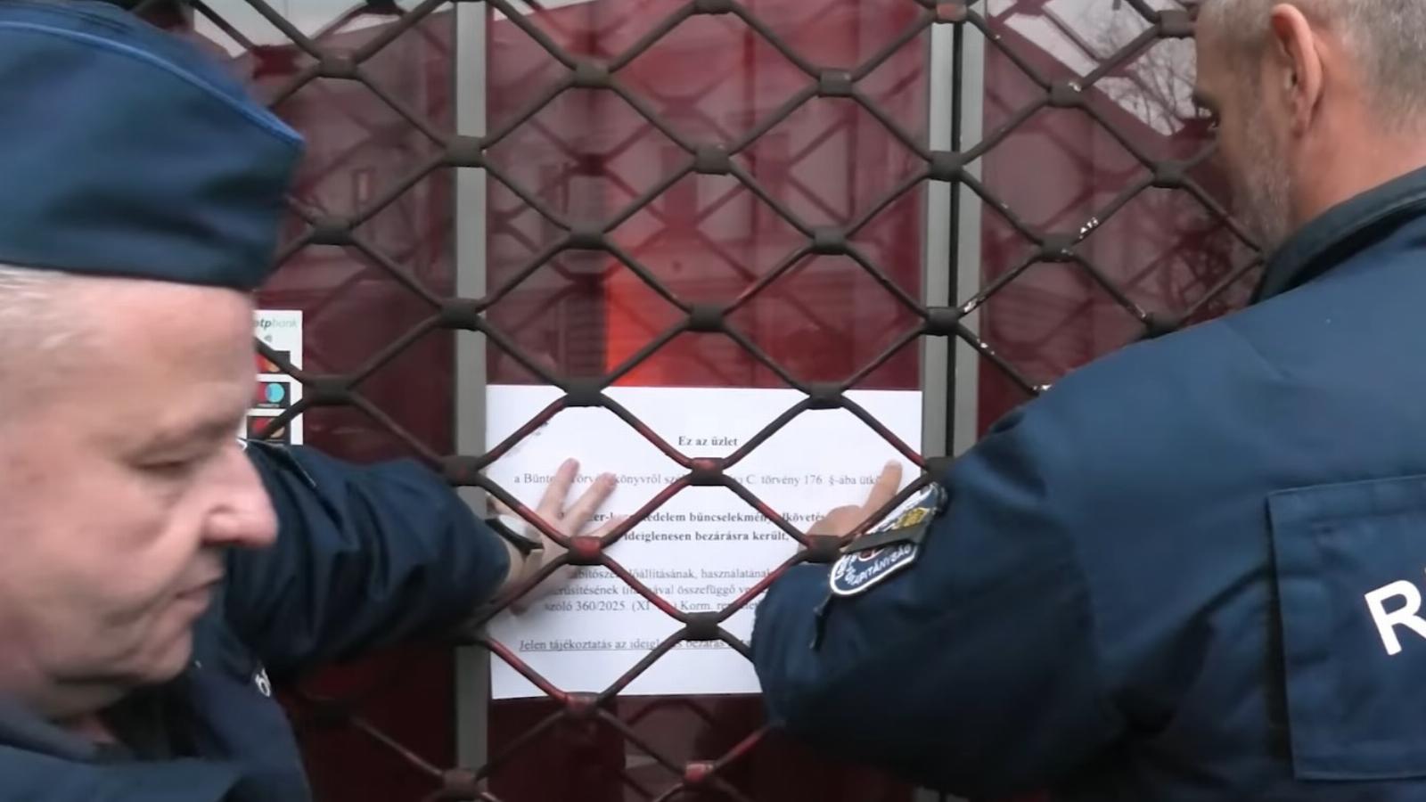 Rendőrök helyezik ki a bezárás okáról szóló tájékoztatót.