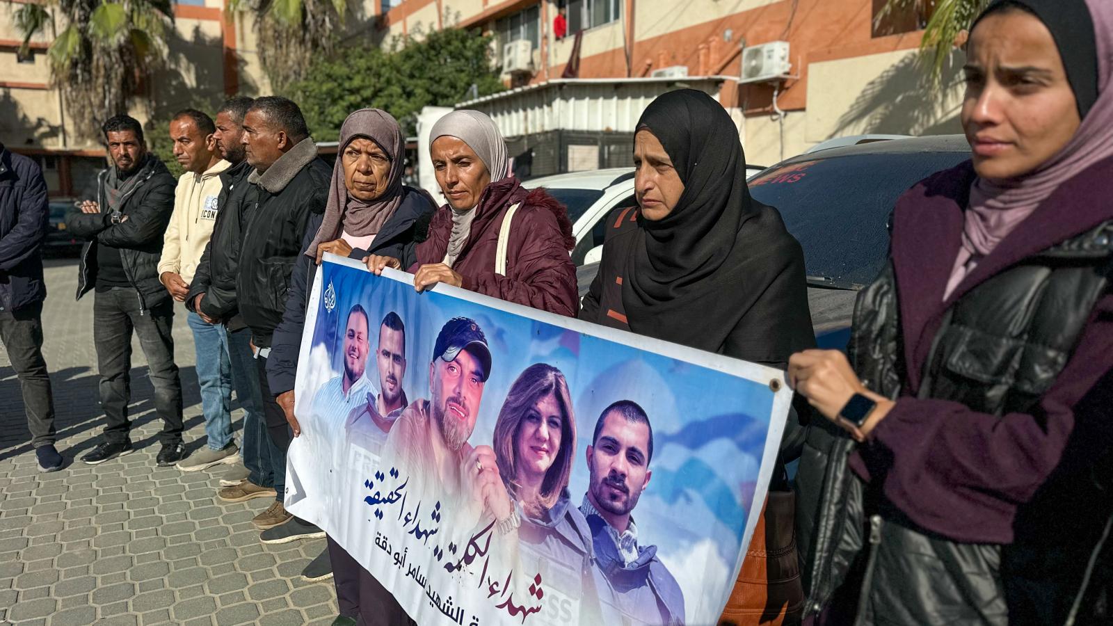 Újságírók és családtagok meggyilkolt sajtómunkások fényképeivel ellátott plakátokat tartanak az Al Jazeera palesztin operatőre, Samer Abu Daqqa emlékére rendezett megemlékezésen halálának második évfordulóján, 2025. december 15-én a Gázai övezetben találh