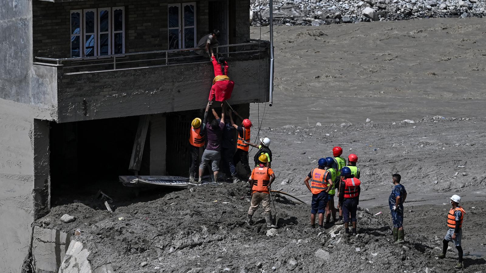 Rendőrök mentenek ki lakosokat egy hordalékkal elöntött házból a Trishuli-folyónál 