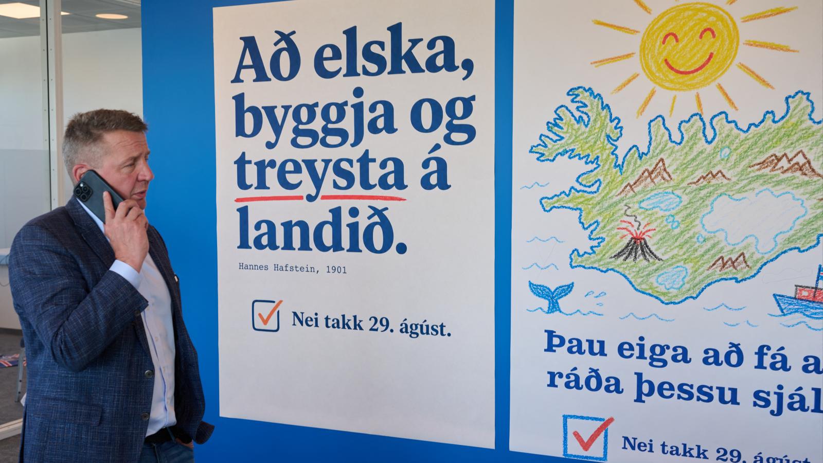 Gudlaugur Thor Thordarson volt izlandi külügyminiszter 2026. augusztus 28-án Reykjavikban egy nemmel szavazásra buzdító plakát mellett 