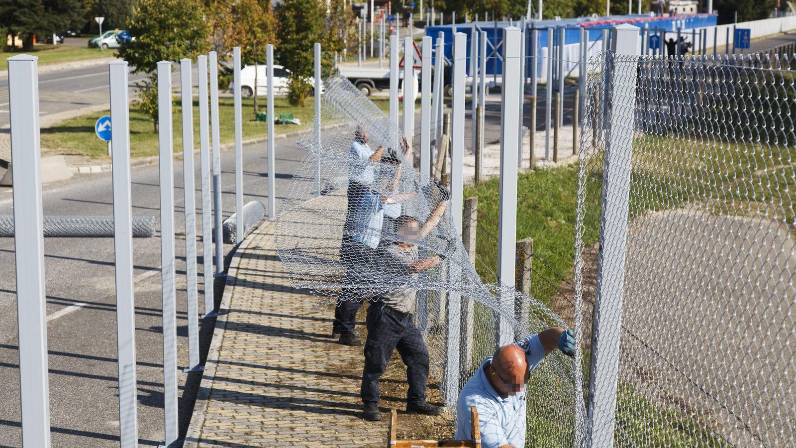 Büntetés-végrehajtási dolgozók az illegális bevándorlók számára kialakított áteresztő ponthoz vezető folyosó kerítését építik a 