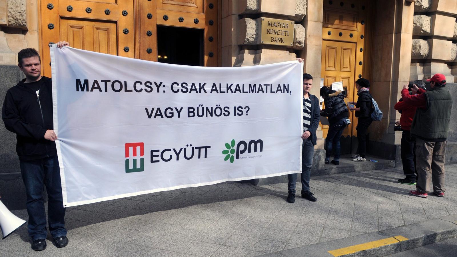 Az Együtt-PM szövetség aktivistái "Matolcsy: csak alkalmatlan vagy bűnös is?" feliratú molinót tartanak demonstrációjukon a Magy