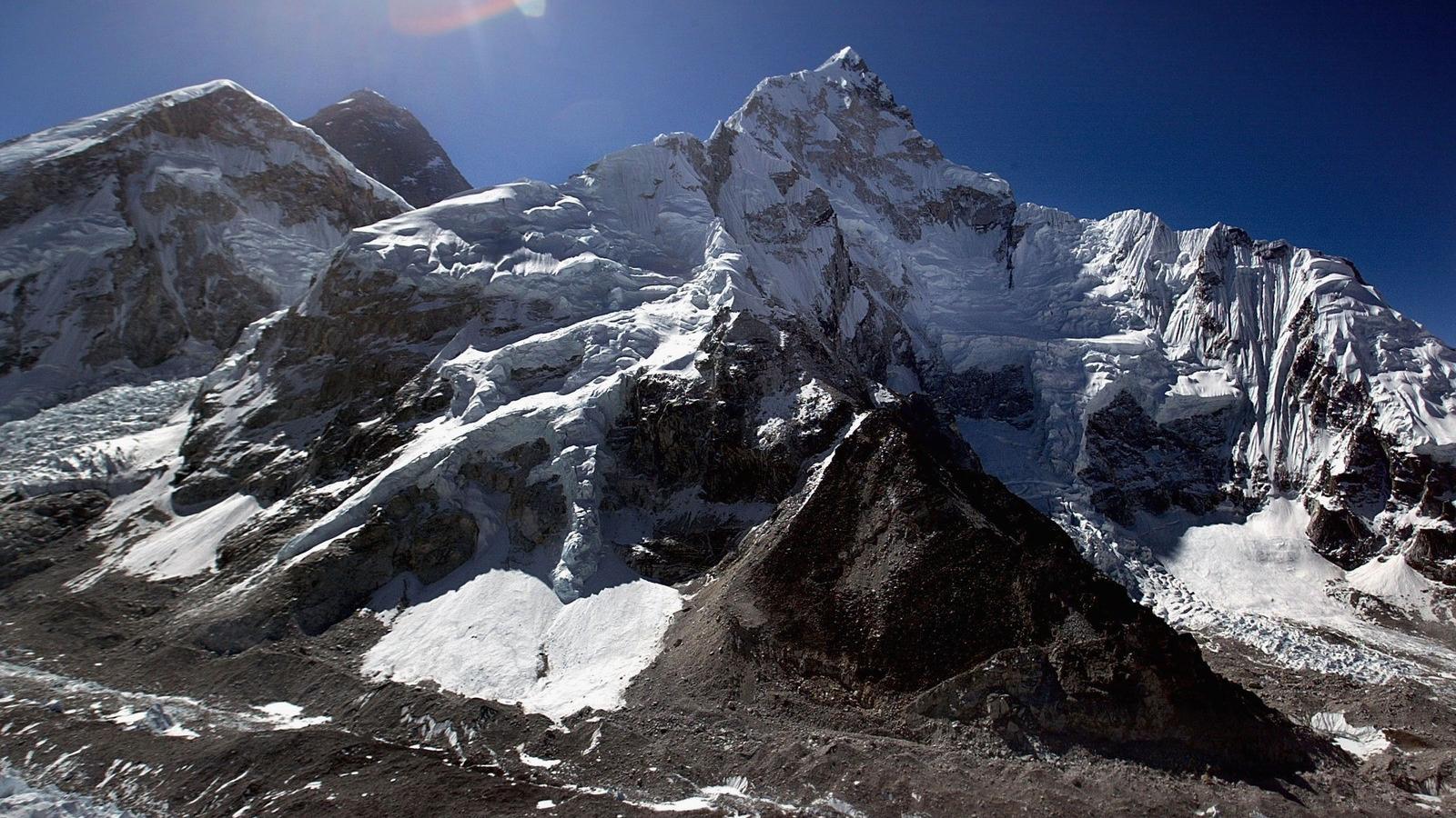 Előtérben a 8516 méter magas Lhoce (j). Balra a háttérben emelkedik a világ legmagasabb hegycsúcsa, a Mount Everest (k). Ennek a