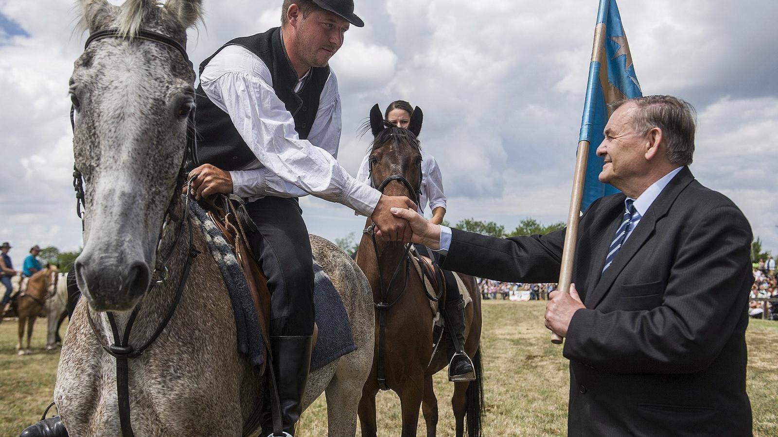 Lezsák Sándor, az Országgyűlés alelnöke (j) átveszi a székely zászlót Abos Zsolttól, a Csíksomlyóról érkezett lovas küldöttség v